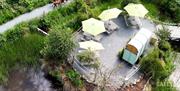 Aerial view of a luxury A-frame lodge nestled among woodland, with ponds, walking paths and green countryside surrounding the retreat.