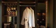 Luxury suite, open wardrobe with hanging robe, towels, and drinks station.