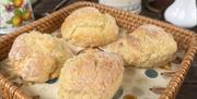 A wicker basked lined with a pretty napkin contains four fresh scones.