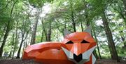 An image of Ssssh - Rusty the fox. The orange fox has a black nose with white ears and white cheeks with the tip of the tail in white. The fox is part