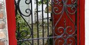 Image shows wrought iron gate into courtyard.