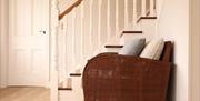 Image shows armchair with cushions and stairway