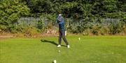 image of man playing teeing off with golf ball