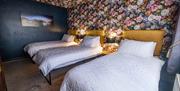 Image shows 3 single beds with lamps and side tables