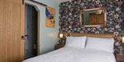 Image shows double bed with mirror above the bed and sliding door leading to ensuite