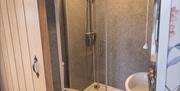 Image shows sliding door into small ensuite with shower, sink & toilet