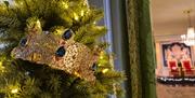An image of a Christmas tree by the entrance to the Throne Room. The tree has lights and a gold crown with jewels.