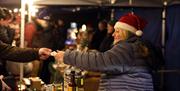 Lady with Santa hat selling at a stall at Christmas Market