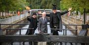 Councillor Beckett with 2 entertainers dressed in black with one carrying a torch and one with a raven on his hat