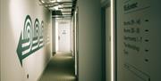 Image shows hotel corridor with showing directions for rooms, apartments, gym and workshop