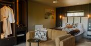 Luxury suite with bed, sofa and robe hanging in open wardrobe