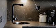 Kitchen counter with sink, coffee machine, and utensils.