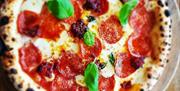 Image shows a pepperoni pizza on a table at the market