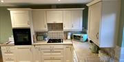 Image shows kitchen area with all mod cons visible and wooden flooring