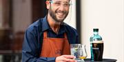 A staff member serving food at the Brasserie wearing PPE