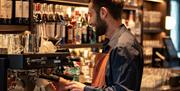 A member a staff making coffee by the coffee machine