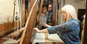 Couple watching a lady using the loom
