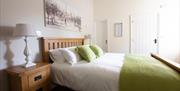 Image shows double bedroom with side tables and lamps