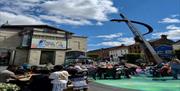 People sitting outside the Irish Linen Museum in Market Square watching a movie on the big screen and enjoying the sunshine.