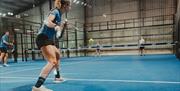 Image shows 4 individuals playing Padel tennis on a blue court.
