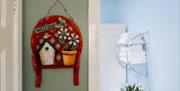 Image shows welcome sign hanging on the wall outside bathroom and a view of white towels folded on a shelf on the bathroom wall