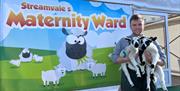 Image shows two Streamvale Farm Lambs being held outside of 'Streamvale's Maternity Ward'.