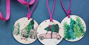 Christmas baubles on pink ribbon with Christmas trees, cars and houses on them
