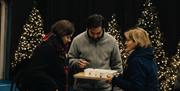 Couple sampling drinks at Tedberry Market with Christmas Trees lit up in the background