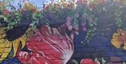 Image is of brick wall painted with colourful flowers