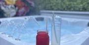Image is of a hot tub with a glass drink sitting on the side