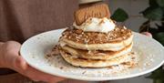 An image of a pancake stake topped with cream and a lotus biscuit