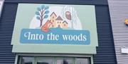 Into the Woods logo sign business name with fox, owl, tree and houses