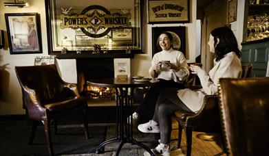 Women drinking coffee by the fire in the Hillside Bar, Royal Hillsborough