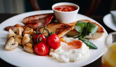 Image of plated breakfast with beans, egg, mushrooms, tomato and bacon