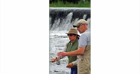 Image is of man showing woman how to fish