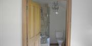 Image shows shower over bath plus toilet through open doorway