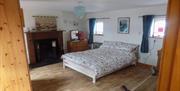 Image shows double bedroom with wooden floor, fireplace, dressing table with mirror.