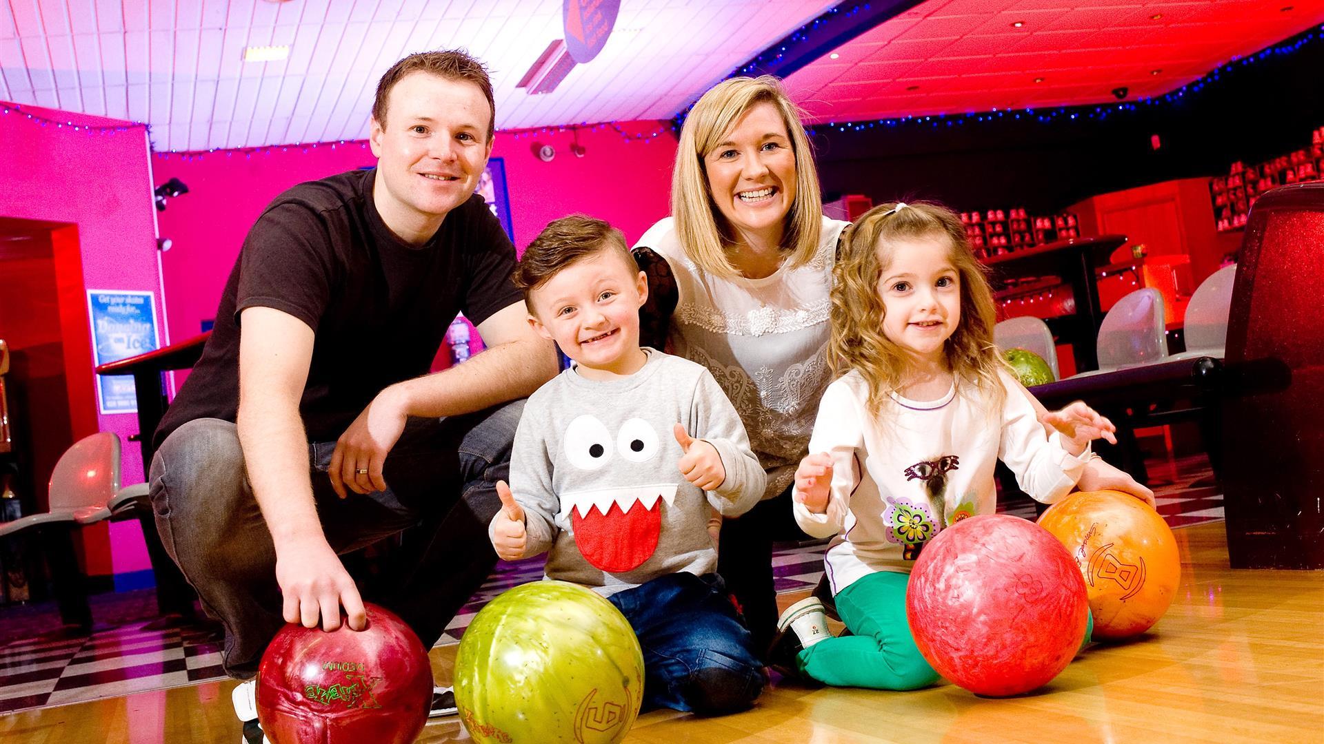 Image is of a family posing for a photo in the bowling alley