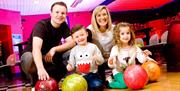 Image is of a family posing for a photo in the bowling alley