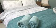 Image shows double bed with rolled up towels at the bottom