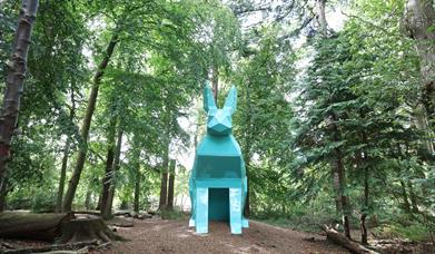 An image of Peep the Hare part of the digital sculpture trail, the hare is teal and is located in the forest park.