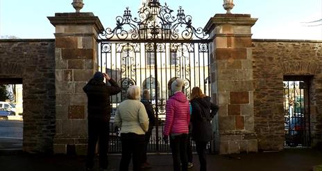 Image shows members of a walking group standing at the gates of Hillsborough Castle