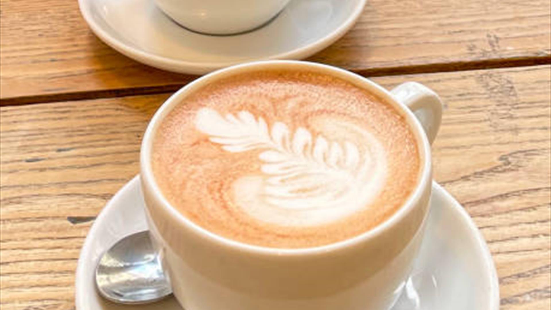 Image shows two white cups with latte coffees