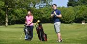 Image is of woman and man golfing on course