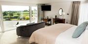 Shows image of double bedroom with large window looking out at countryside view