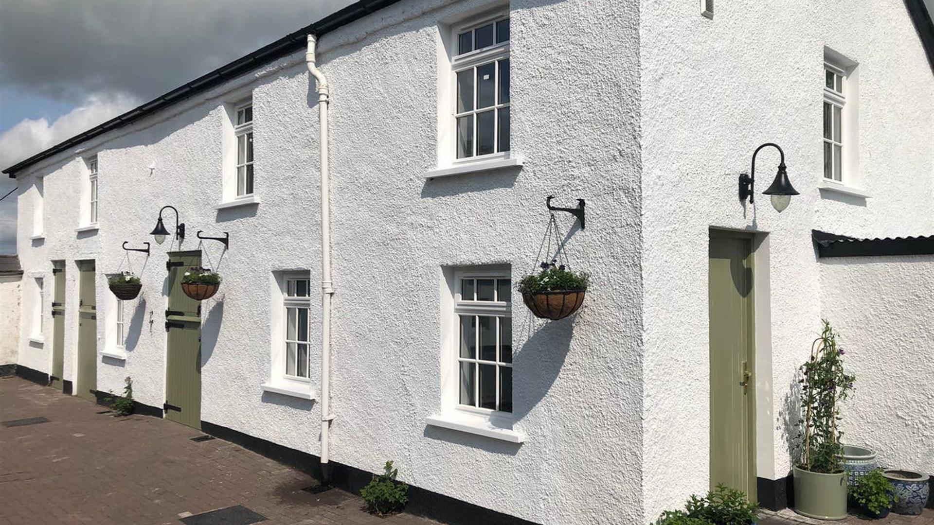 Image shows front of property - whitewashed and with hanging baskets