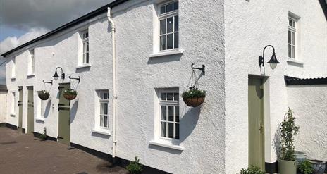 Image shows front of property - whitewashed and with hanging baskets