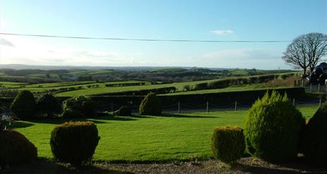Image shows lawn in front of property with view of the countryside beyond