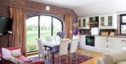 Image shows lady standing in kitchen dining area looking out feature arch window
