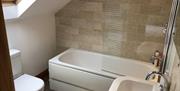 Image shows bath/overhead shower, sink and toilet